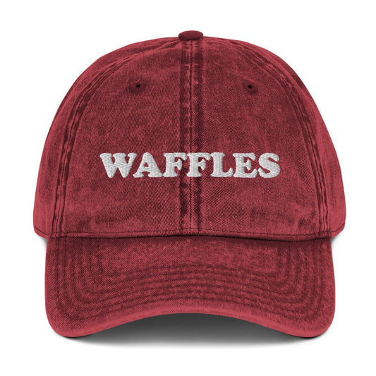 Washed out red denim dad hat for waffle lovers - The Waffles Dad Hat! This funny food dad hat is the perfect everyday accessory to show off your love of waffles. Wear the unique foodie dad hat for any occasion or give it as a stylish weird gift for a waffle lover. Show off your love of waffles and favorite foods in our vintage style weird dad hats and clothing.