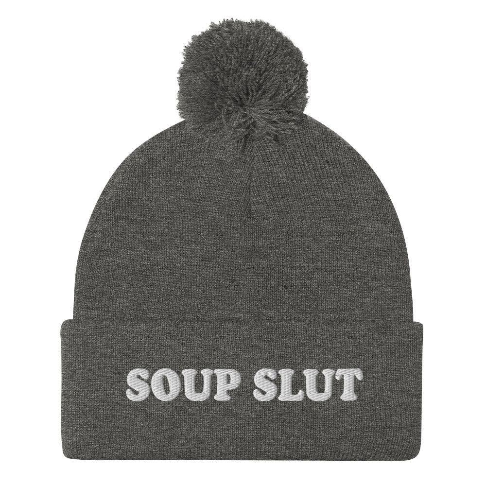 Gray Embroidered Beanie with Soup Slut from Nina's Funky Shop - Love soup? Looking for a funny gift for a soup enthusiast? This warm and cozy, embroidered beanie is just what you need. It's a classic pom pom beanie with "soup slut", expertly embroidered on the front. The perfect weird beanie hat for soup sluts and foodies of all kinds. Celebrate your favorite foods in our funky foodie apparel.